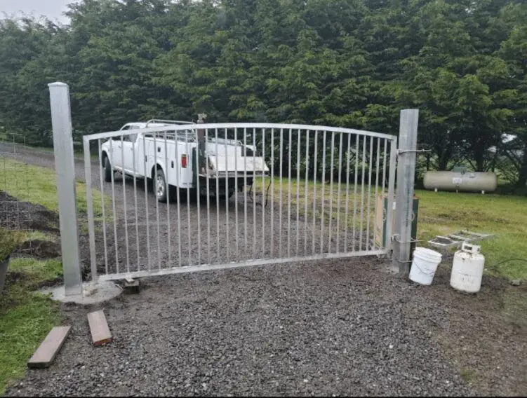 A white vehicle parked behind a metal gate